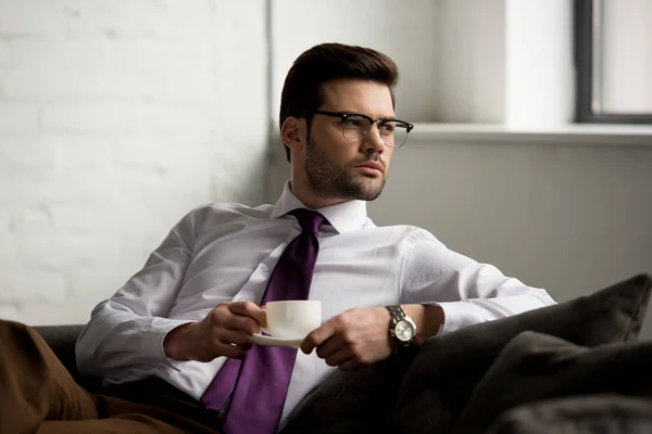 Bild eines Geschäftsmannes in Gläsern, der mit einer Tasse Kaffee sitzt — Stockfoto