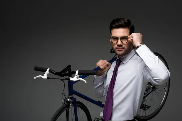 Portrait of businessman in glasses holding bicycle isolated on grey — Stock Photo