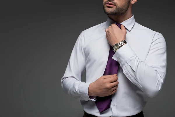 Обрізане зображення бізнесмена, що виправляє краватку ізольовано на сірому ізольовано на сірому — стокове фото