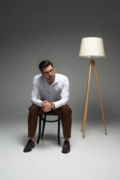 Бизнесмен, сидящий на стуле у пола на сером — стоковое фото