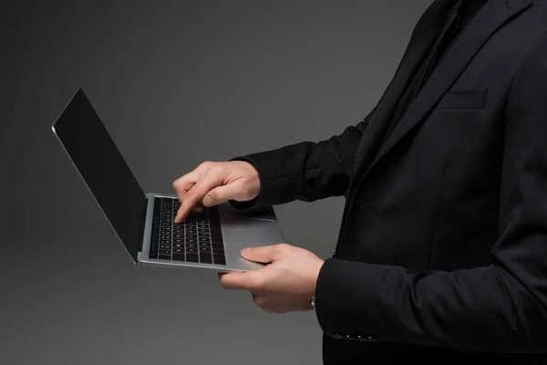 Vista parcial do empresário segurando laptop em mãos isoladas em cinza — Fotografia de Stock