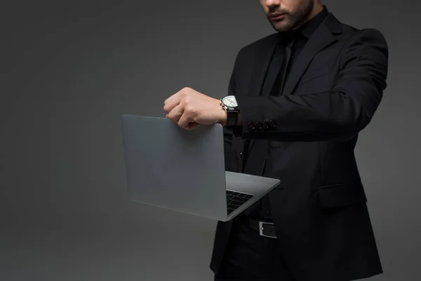 Vista recortada de hombre de negocios con estilo con ordenador portátil en manos aisladas en gris - foto de stock