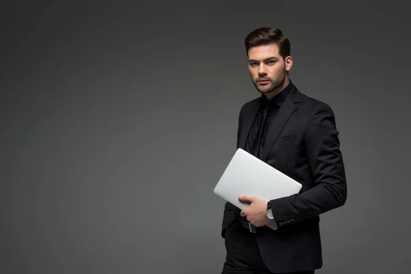 Ritratto di giovane uomo d'affari con laptop in mano isolato su grigio — Foto stock