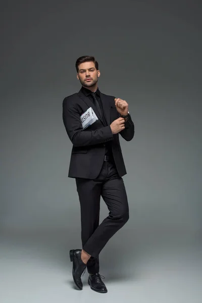Elegante uomo d'affari in piedi con giornale su grigio — Foto stock