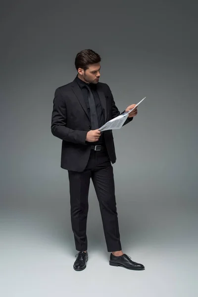 Вид бізнесмена, що стоїть і читає газету на сірому — стокове фото