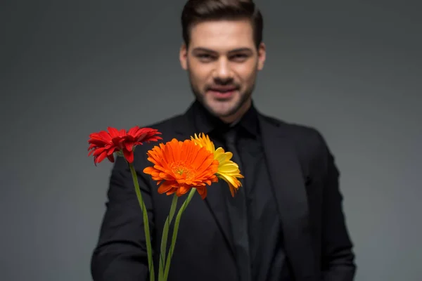 Lächelnder Mann mit Blumenstrauß auf grauem, internationalem Frauentag-Konzept — Stockfoto