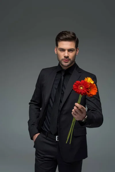 Elegante y con ramo de flores aislado en gris, concepto de día internacional de la mujer - foto de stock