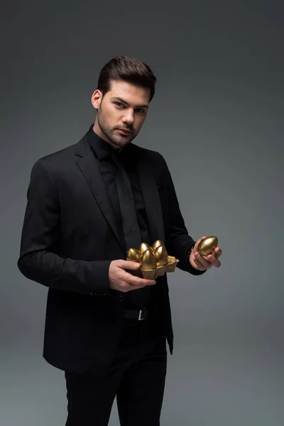 Portrait of male holding golden eggs isolated on grey, easter concept — Stock Photo