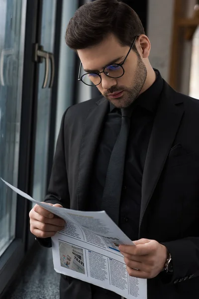 Young businessman in glasses reading newspaper — Stock Photo