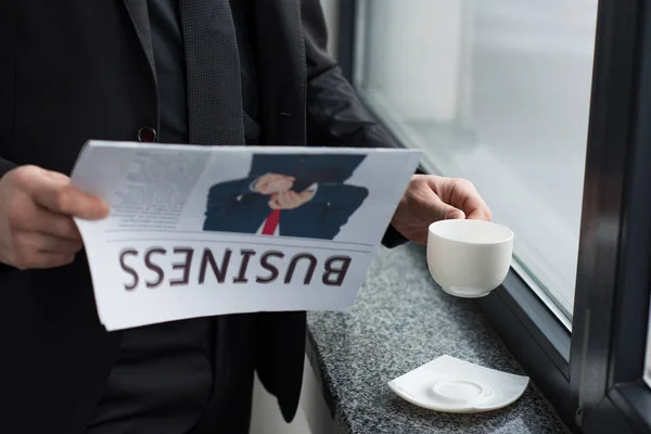 Teilansicht des Geschäftsmannes, der Zeitung liest und Kaffeetasse hält — Stockfoto
