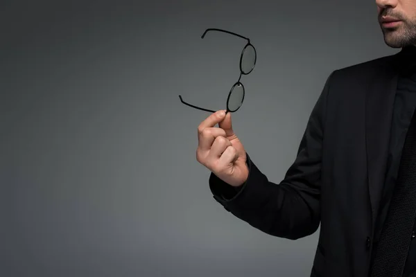 Vista parcial del hombre elegante sosteniendo gafas aisladas en gris - foto de stock