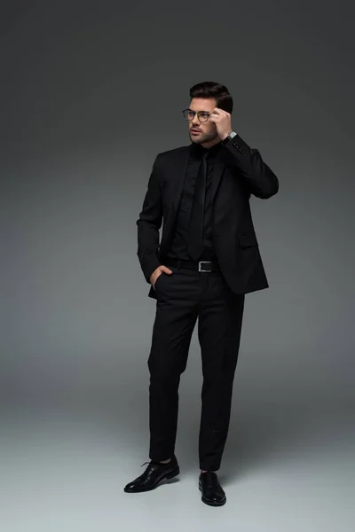 Stylischer junger Mann in Brille posiert auf grau — Stockfoto