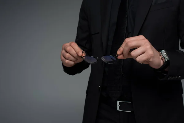 Vista parcial de las manos masculinas sosteniendo gafas aisladas en gris - foto de stock