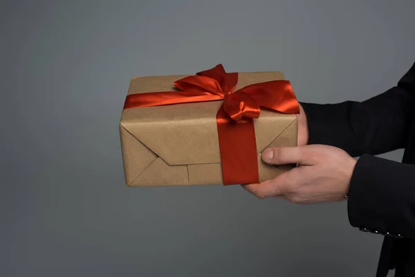 Крупним планом подарункова коробка в чоловічих руках ізольована на сірому, міжнародному жіночому концепті дня — стокове фото