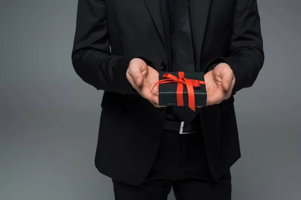 Vista parcial de manos masculinas sosteniendo caja de regalo aislada en gris, concepto de día internacional de la mujer - foto de stock