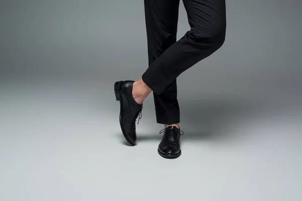 Частичный вид мужских ног в черных формальных туфлях на сером — стоковое фото