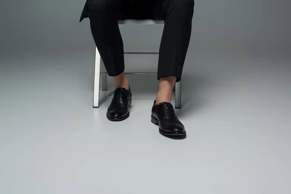 Частковий вигляд чоловічих ніг у стильному формальному взутті на сірому — стокове фото