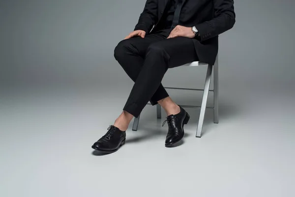 Vista parcial del hombre con estilo en traje sentado en gris - foto de stock