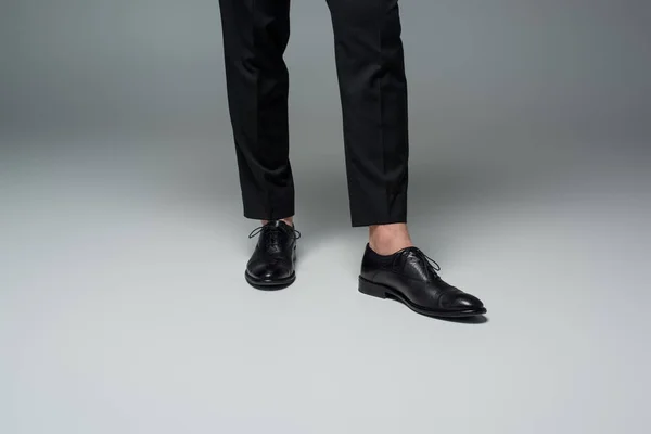 Частичный вид стильных мужских ног в черных формальных туфлях на сером — стоковое фото