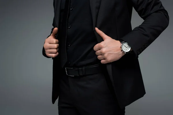 Vista parcial de mãos masculinas segurando jaqueta isolada em cinza — Fotografia de Stock