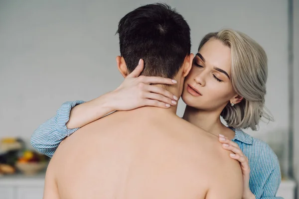 Passionate girlfriend hugging shirtless boyfriend at kitchen — Stock Photo