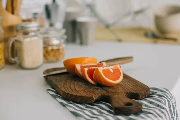 Cut grapefruit with knife on cutting board in kitchen — Stock Photo