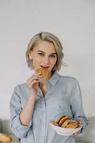 Beautiful girl biting oat cookie at home — Stock Photo