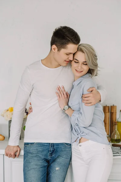 Handsome boyfriend hugging attractive girlfriend at kitchen — Stock Photo