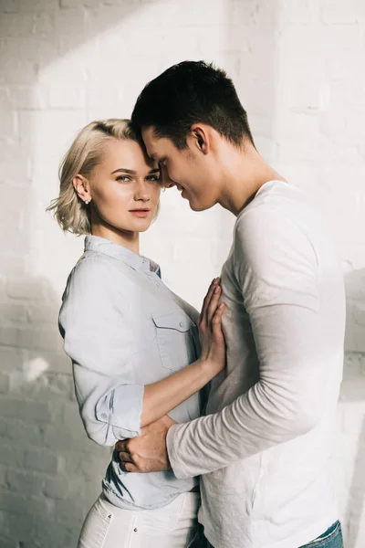 Attractive girlfriend looking at camera when boyfriend hugging her at home — Stock Photo