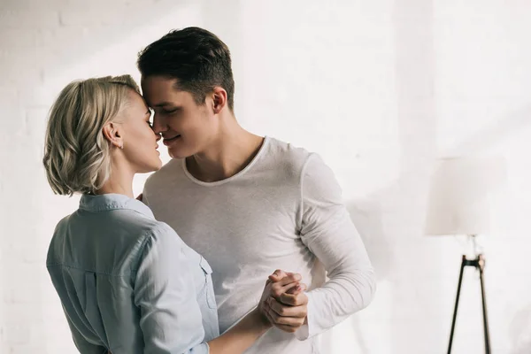 Sexy pareja cogida de la mano y besos en casa - foto de stock