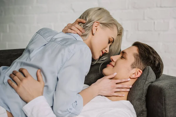 Sexy couple lying on sofa and hugging at home — Stock Photo