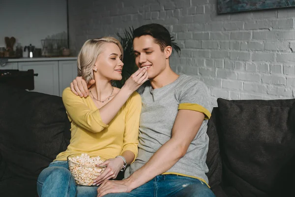 Fidanzata sorridente alimentazione fidanzato con popcorn — Foto stock