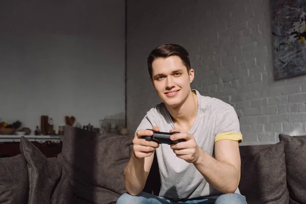 Smiling handsome man holding joystick and looking at camera — Stock Photo