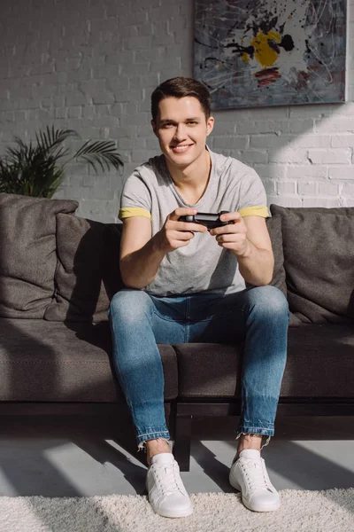 Sorrindo homem bonito segurando almofada de jogo e olhando para a câmera — Fotografia de Stock