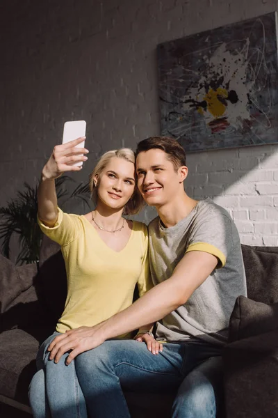 Feliz pareja tomando selfie con smartphone en casa - foto de stock