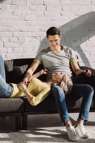 Happy girlfriend lying on boyfriends legs in living room at home — Stock Photo