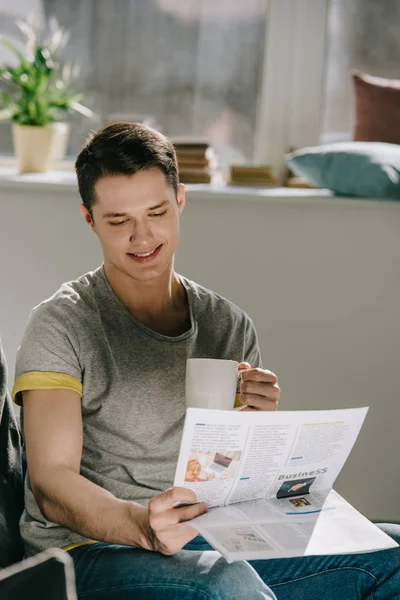 Homem bonito beber café e ler jornal em casa — Fotografia de Stock