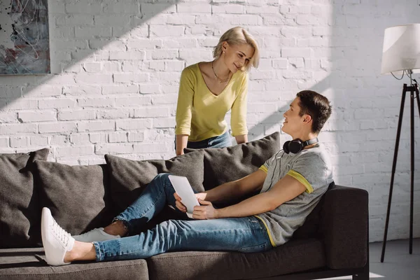 Boyfriend using tablet and looking at girlfriend at home — Stock Photo