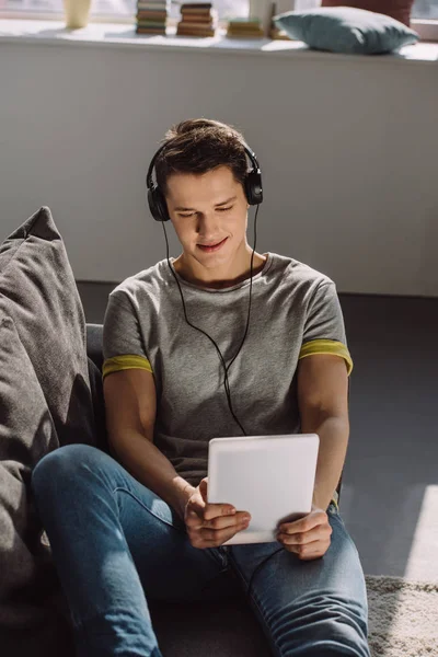 Sorrindo bonito homem assistindo filme no tablet em casa — Fotografia de Stock