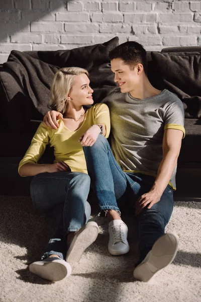 Couple assis sur le sol et étreignant à la maison — Photo de stock