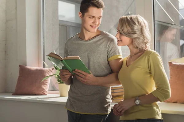 Girlfriend looking into boyfriends book at home — Stock Photo