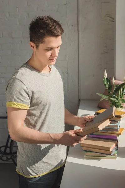 Homem bonito escolhendo livro para ler em casa — Fotografia de Stock