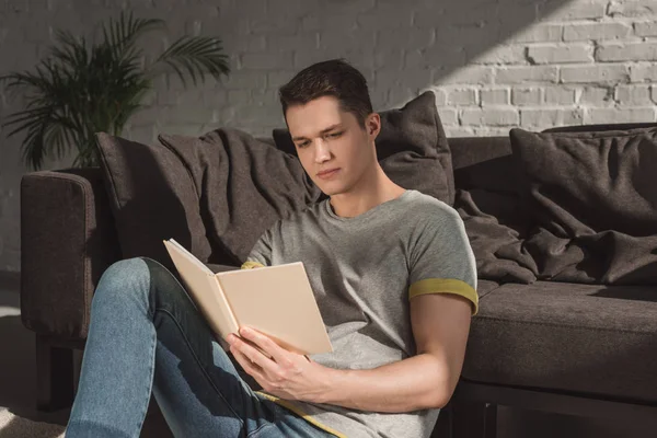 Schöner Mann liest Buch im Wohnzimmer — Stockfoto