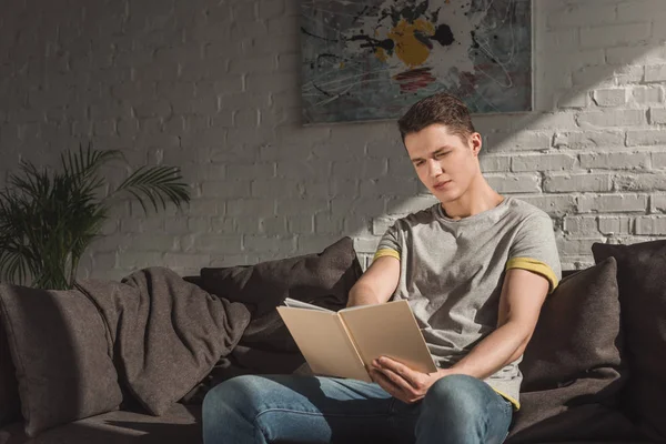 Beau livre de lecture homme sur canapé — Photo de stock