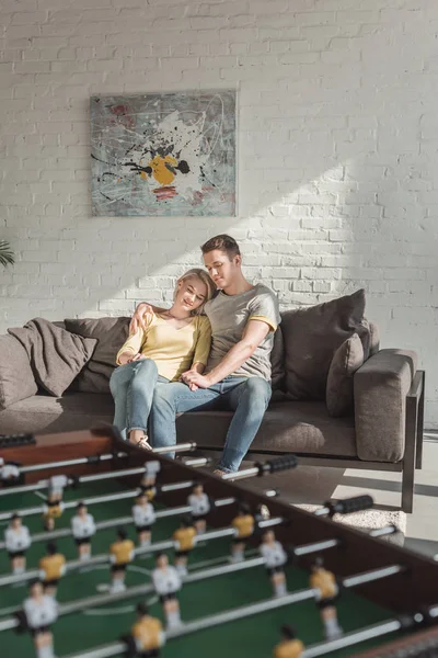 Casal abraçando e sentado no sofá na sala de estar em casa — Fotografia de Stock