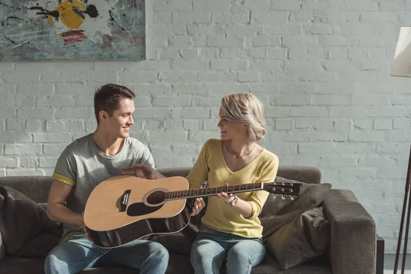 Boyfriend giving acoustic guitar to girlfriend at home — Stock Photo