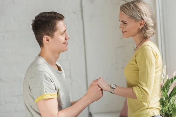 Couple holding hands and looking at each other at home — Stock Photo