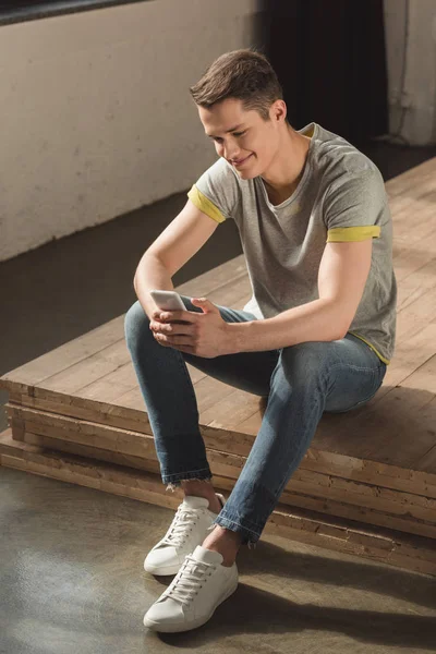 Sorrindo homem bonito usando smartphone em casa — Fotografia de Stock