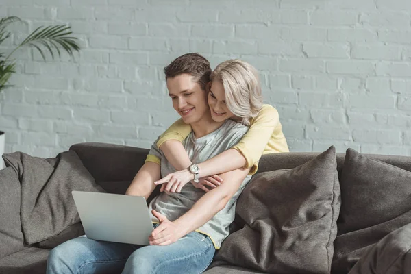 Novia sonriente abrazando novio y apuntando a la computadora portátil — Stock Photo