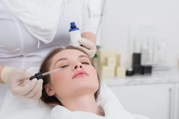 Vista parcial de una mujer joven que recibe tratamiento facial realizado por el cosmetólogo en el salón - foto de stock